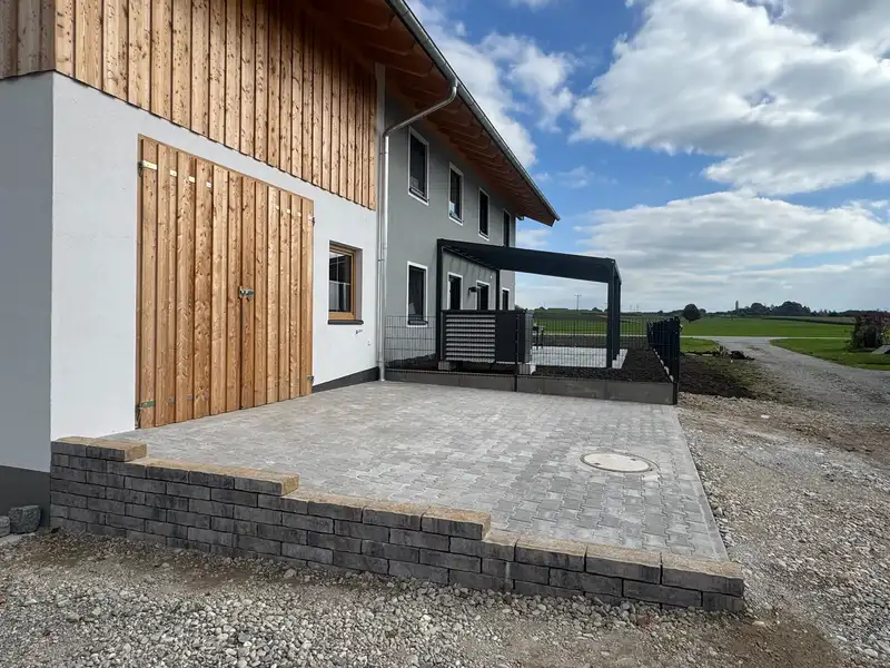 Gepflasterter Hof an einem Haus mit Holzfassade