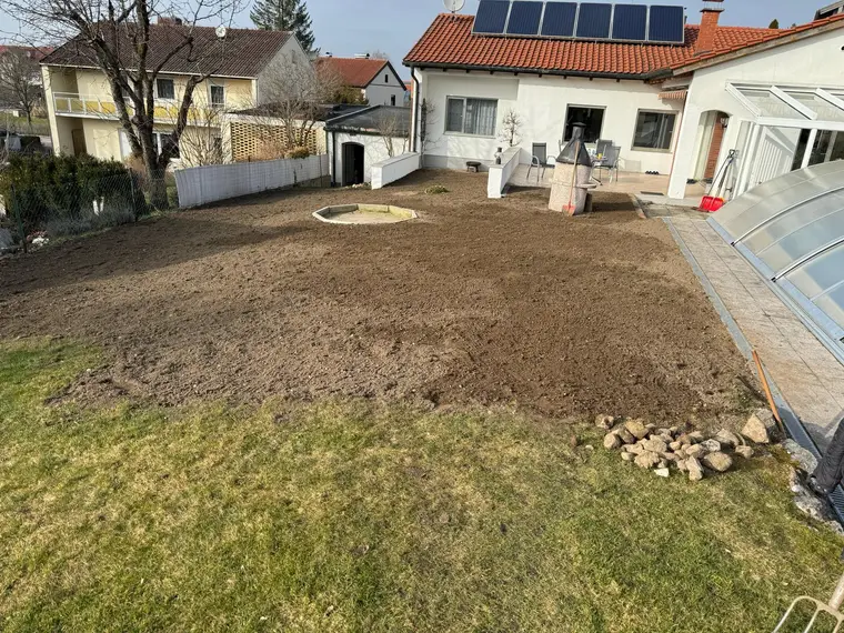 Vorbeiteter Gartenbereich mit frisch umgegrabener Erde hinter Wohnhäusern