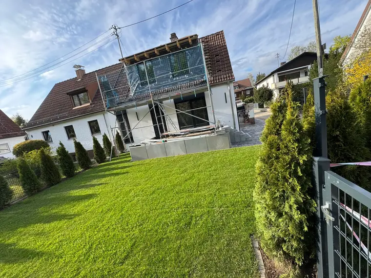Wohnhaus mit Gerüst an der Fassade und grünem Rasen