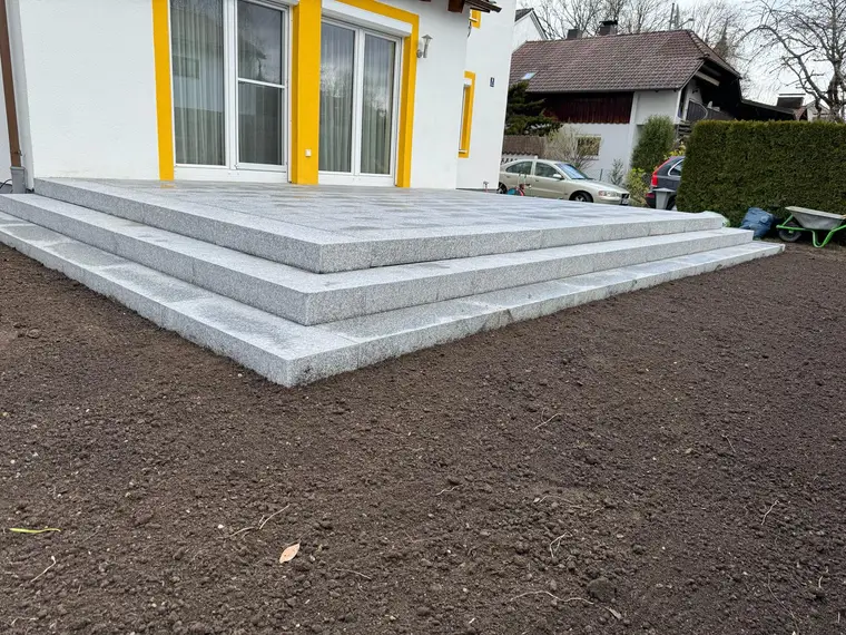 Gepflasterte Terrasse mit Granitstufen an einem Wohnhaus