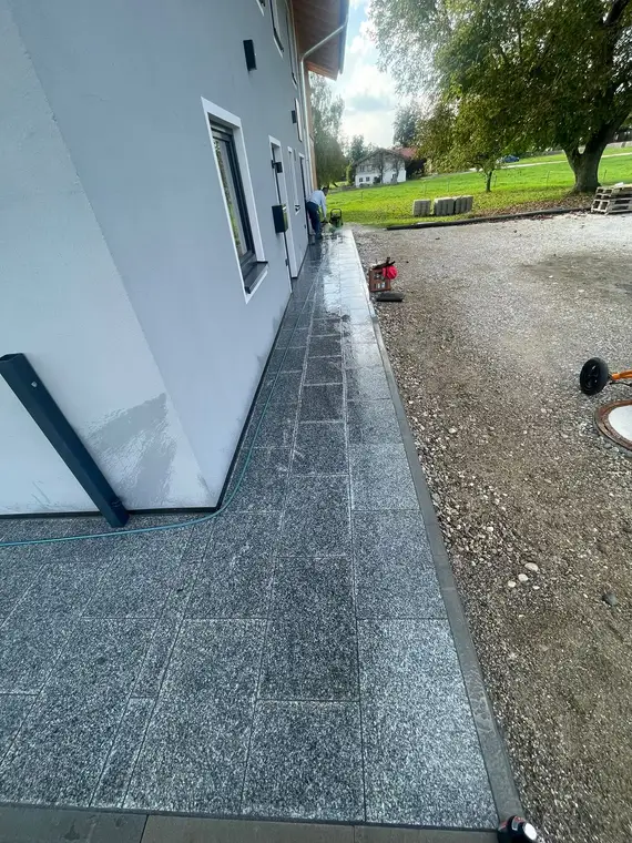Gereinigter Gehweg aus Granitplatten an einer Hausfassade