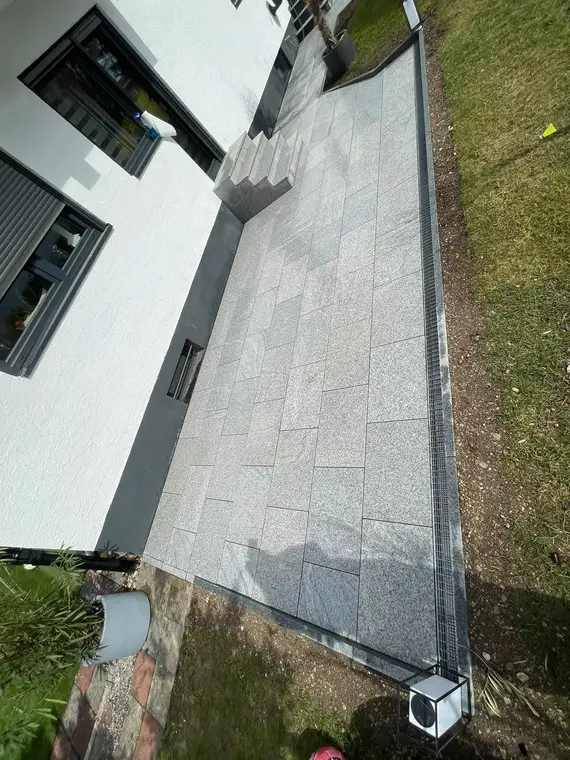 Neu gepflasterte Terrasse aus grauen Steinplatten am Haus