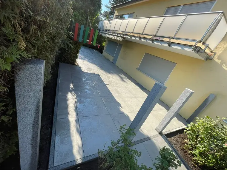 Neu gepflasterte Terrasse mit Granitstehlen neben einem Wohnhaus