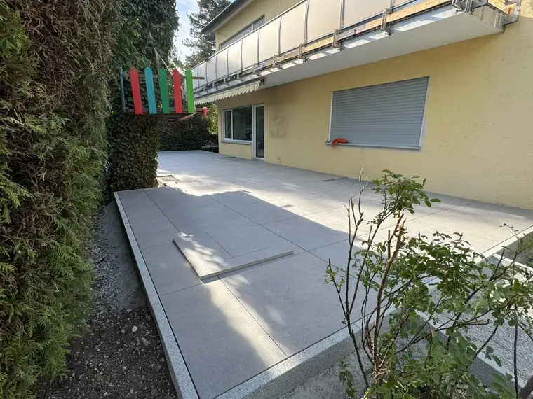 Neu geflieste Terrasse an einem gelben Wohnhaus