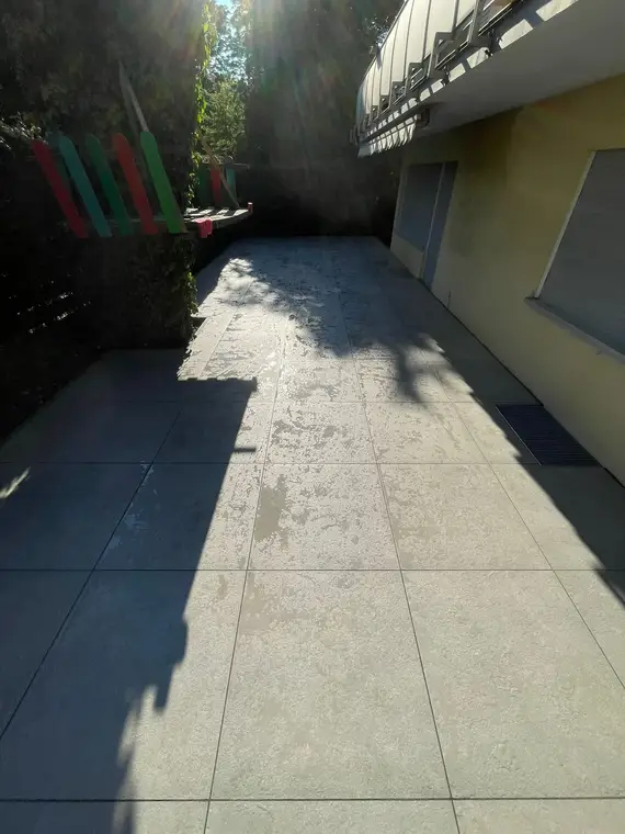 Geflieste Terrasse neben einem Haus im Sonnenschein