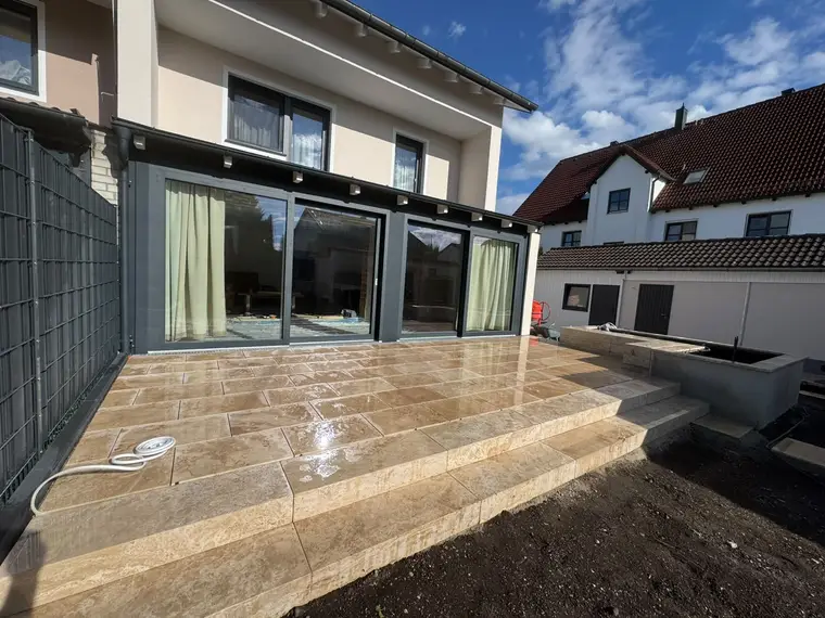 Neugeflieste Terrasse an einem Wohnhaus mit großen Glasfronten