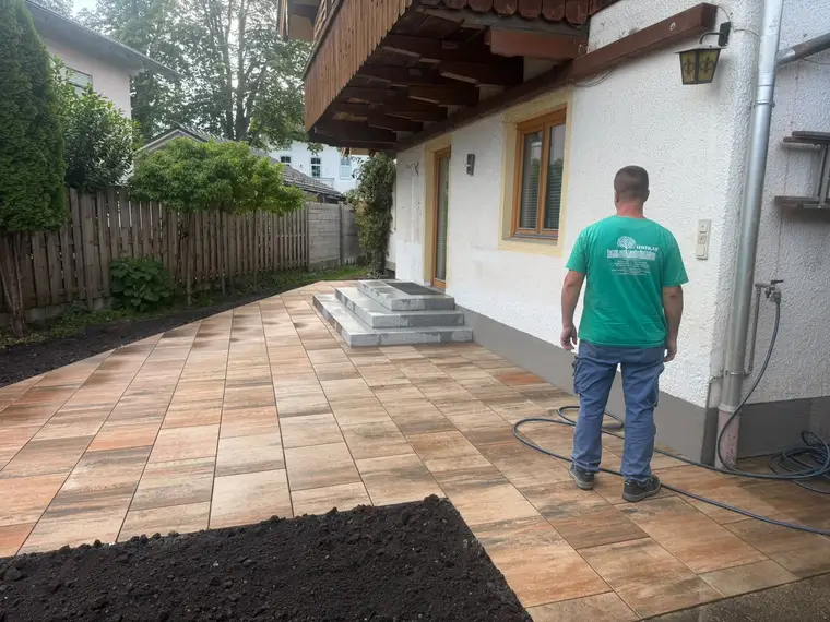 Handwerker steht auf neu verlegter Terrasse am Haus