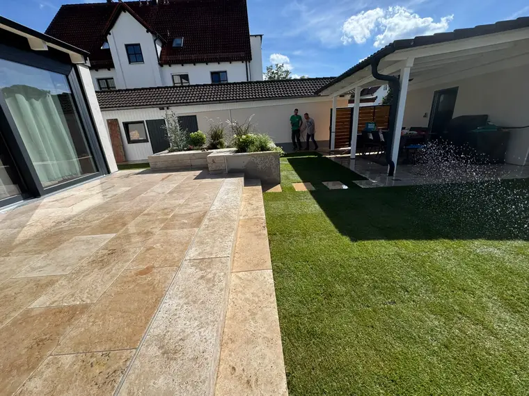 Modern outdoor patio and lawn area being watered