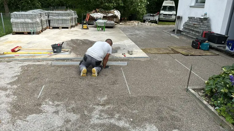 Bauarbeiter zieht Kiesbett auf einer Baustelle glatt