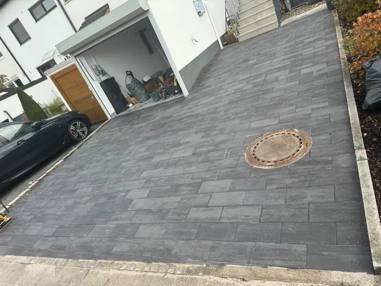 Gepflasterte Hofeinfahrt mit Garageneinfahrt und Gullydeckel