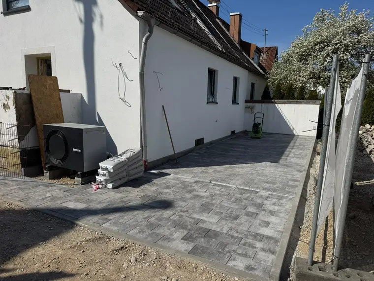 Gepflasterte Einfahrt am Haus mit Buderus-Wärmepumpe und Baumaterialien