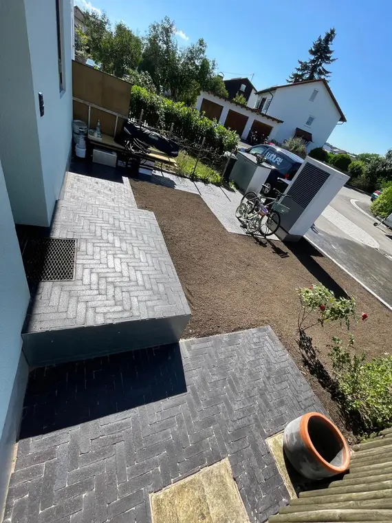 Gepflasterter Eingangsbereich mit frischer Erde und Wärmepumpe