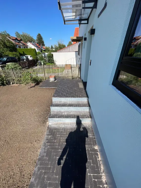Gepflasterter Hauseingang mit Treppenstufen und Vorgarten