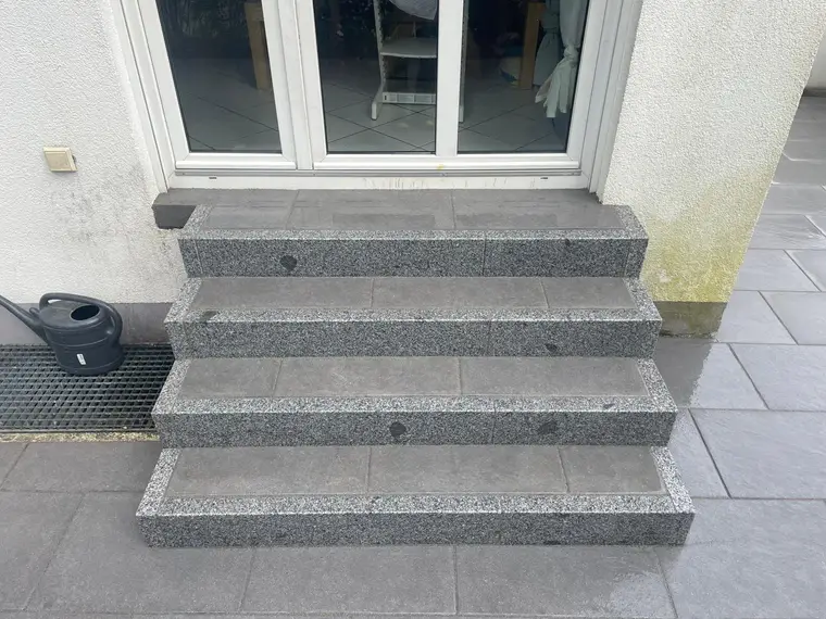 Graue Außentreppe mit Granitstufen vor einer Glastür