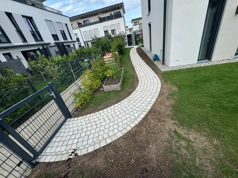 Gepflasterter Gartenweg aus Naturstein zwischen modernen Wohnhäusern