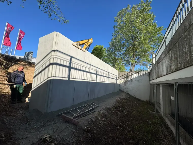Bauarbeiter an einer neuen Betonmauer auf einer Baustelle