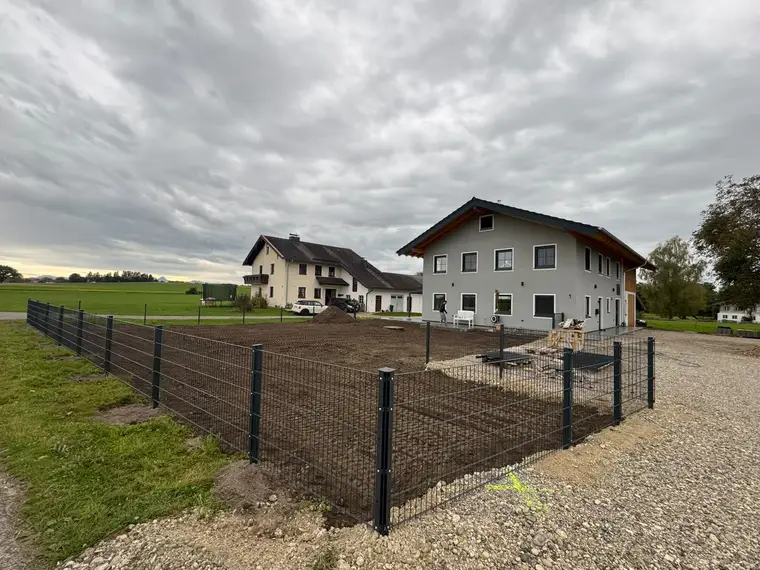 Eingezäunter Gartenbereich mit Erde vor einem Wohnhaus