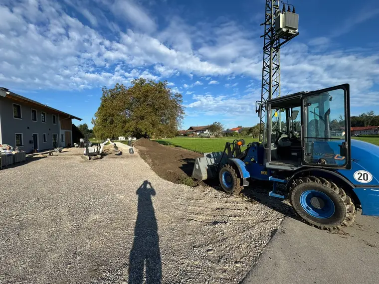 Blaue Radlader und Minibagger bei Erdarbeiten am Grundstück