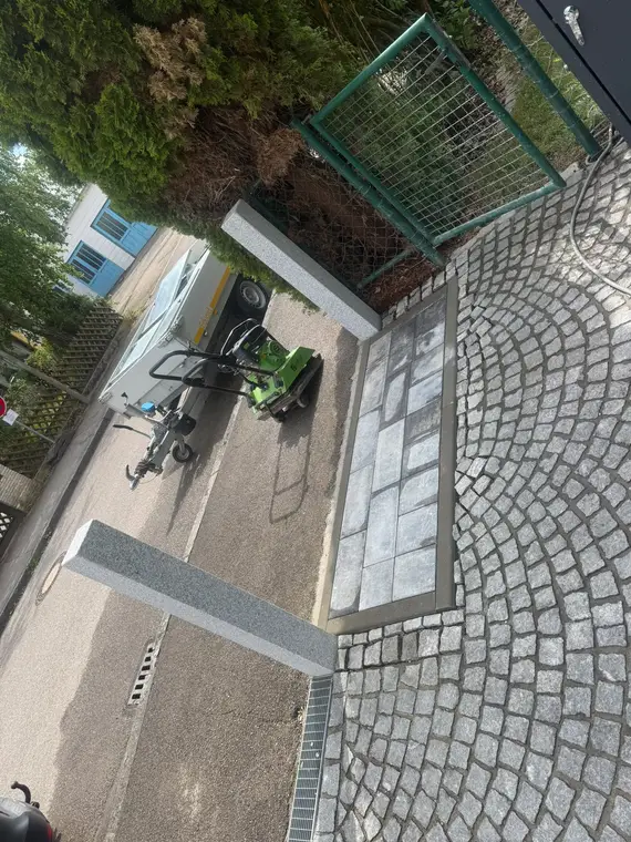 Gepflasterte Einfahrt mit Granitstelen, Rüttelplatte und Anhänger