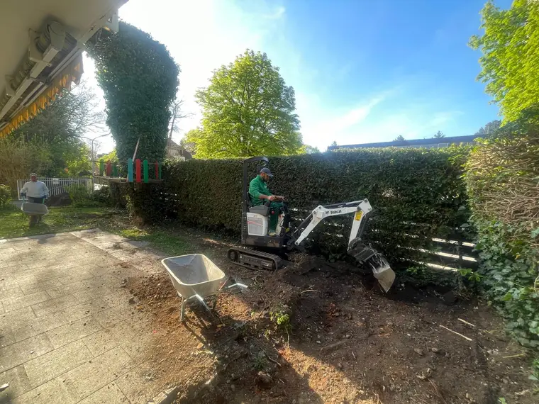 Minibagger und Bauarbeiter bei Erdarbeiten im Garten