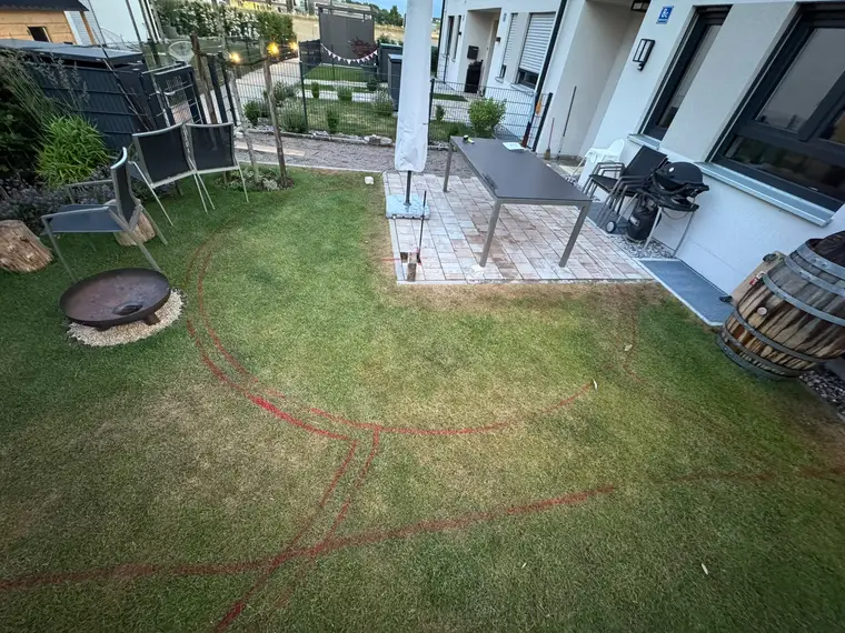 Rasenfläche mit rot aufgesprühter Kreisform vor der Terrasse